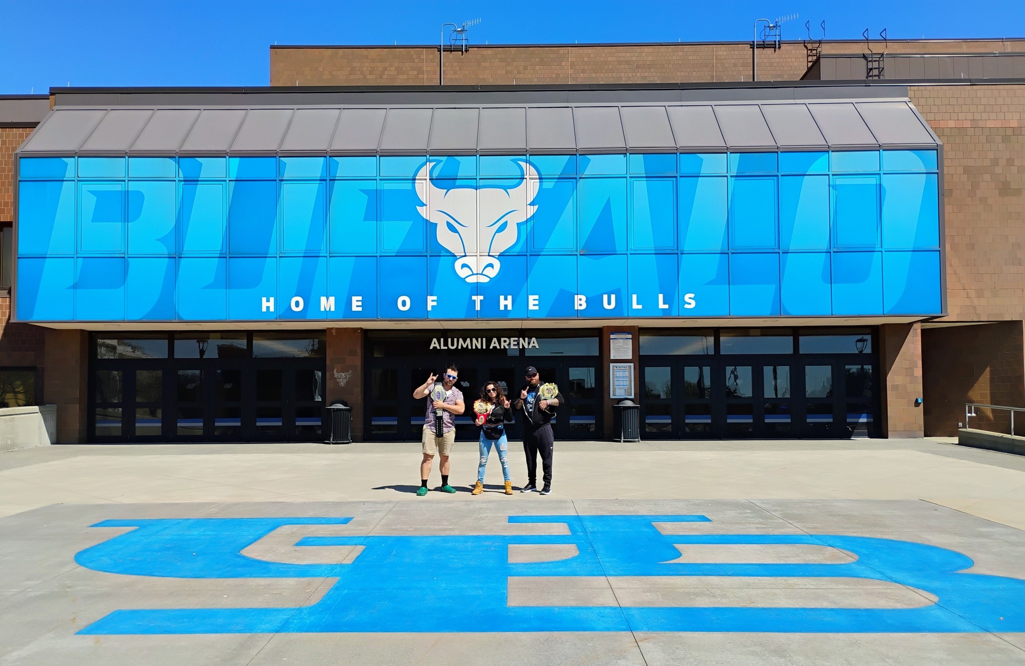 ESW champions Christina Marie, James Sayga, and Vince Valor pose in front of UB